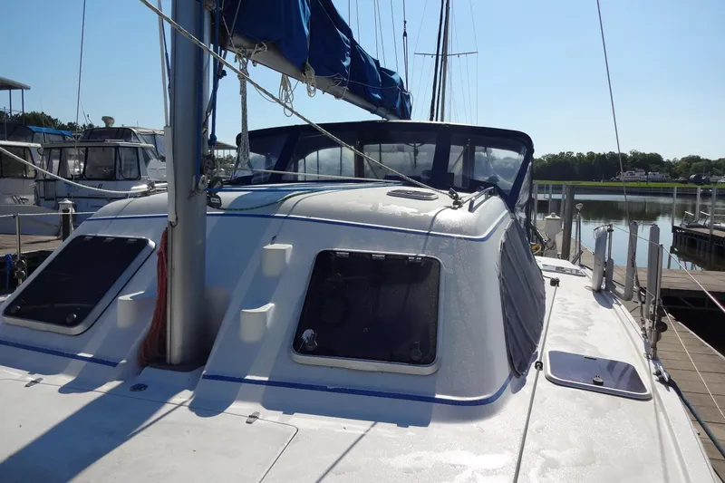 Slide: The Image of 1996 Lagoon 35 CCC sailboat docked at marina, featuring sleek design and blue sail cover. - 56