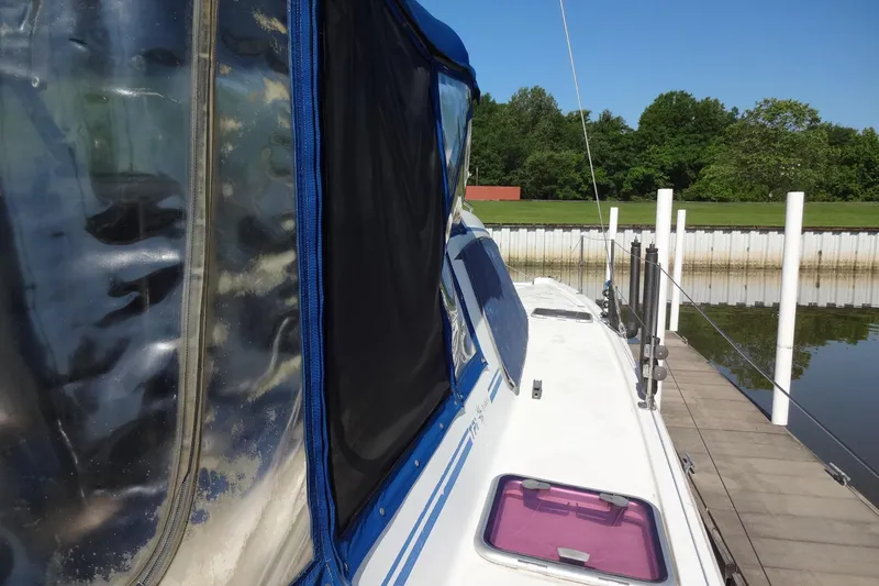 Slide: The Image of 1996 Lagoon 35 CCC sailboat docked, featuring blue and black canopy, with lush greenery background. - 61
