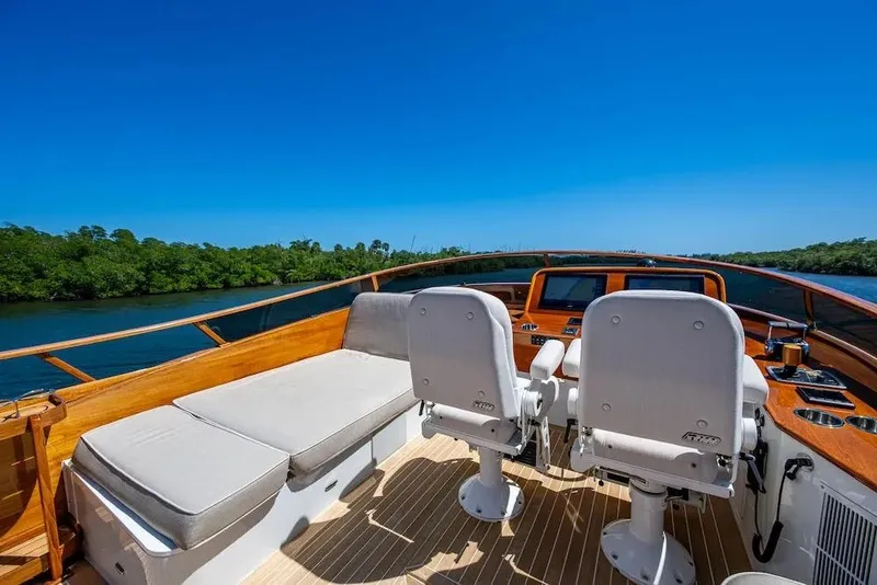 Slide: The Image of 2021 Hinckley Talaria 55 Flybridge MKII, luxurious helm with seating, scenic water view. - 18