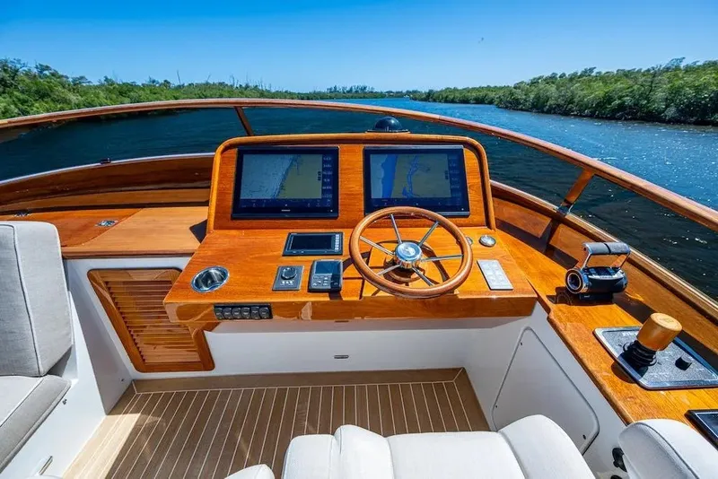 Slide: The Image of Helm of 2021 Hinckley Talaria 55 Flybridge MKII with navigation screens and wooden steering wheel. - 20