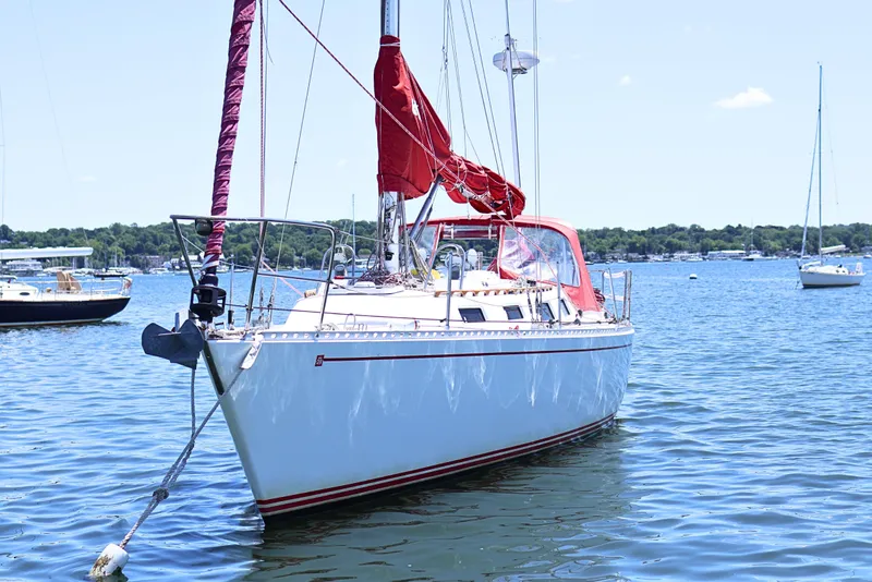 Slide: The Image of 1989 J Boat J 40 sailboat anchored on a sunny day in a serene harbor. - 2