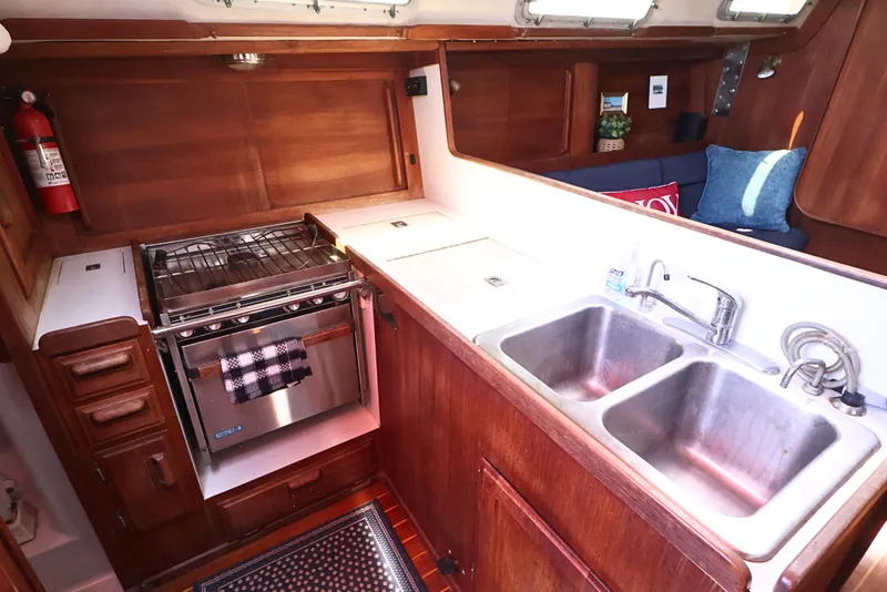 Slide: The Image of 1989 J Boat J 40 interior kitchen with stove, double sink, and wooden cabinetry. - 23