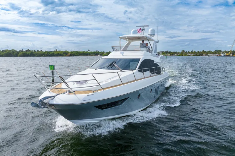 Slide: The Image of 2014 Azimut 54 Flybridge yacht cruising on a scenic waterway under a partly cloudy sky. - 1