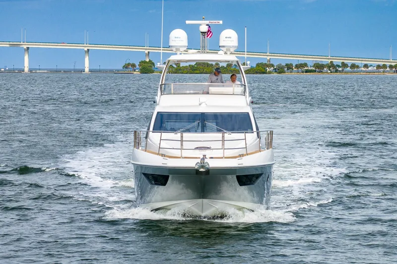 Slide: The Image of 2014 Azimut 54 Flybridge yacht cruising on open water near a bridge. - 10