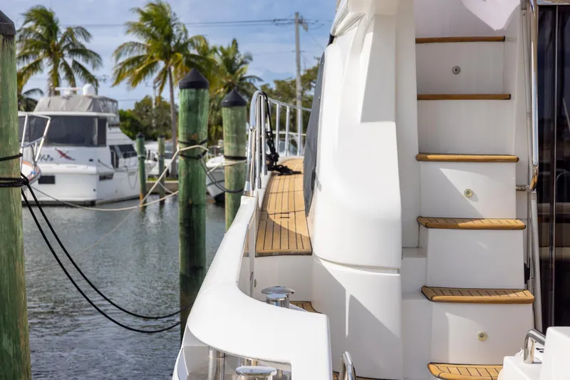 Slide: The Image of 2014 Azimut 54 Flybridge yacht docked, featuring wooden steps and sleek design. - 17