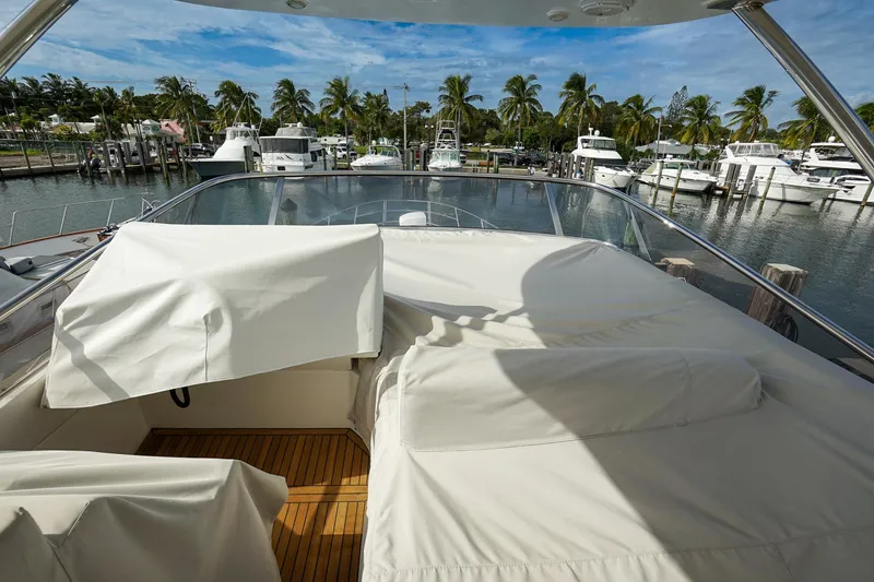 Slide: The Image of 2014 Azimut 54 Flybridge yacht docked, featuring covered seating and scenic marina view. - 26