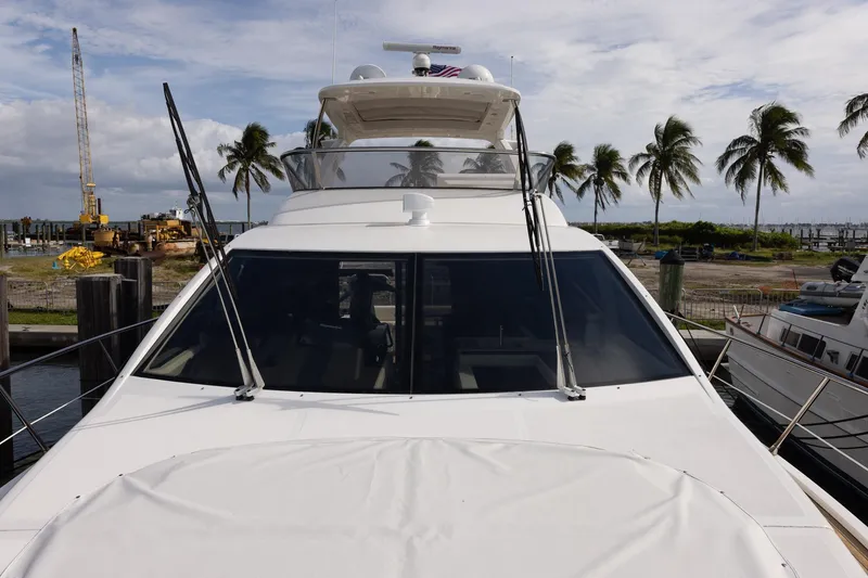 Slide: The Image of 2014 Azimut 54 Flybridge yacht docked, with palm trees and construction equipment in the background. - 94