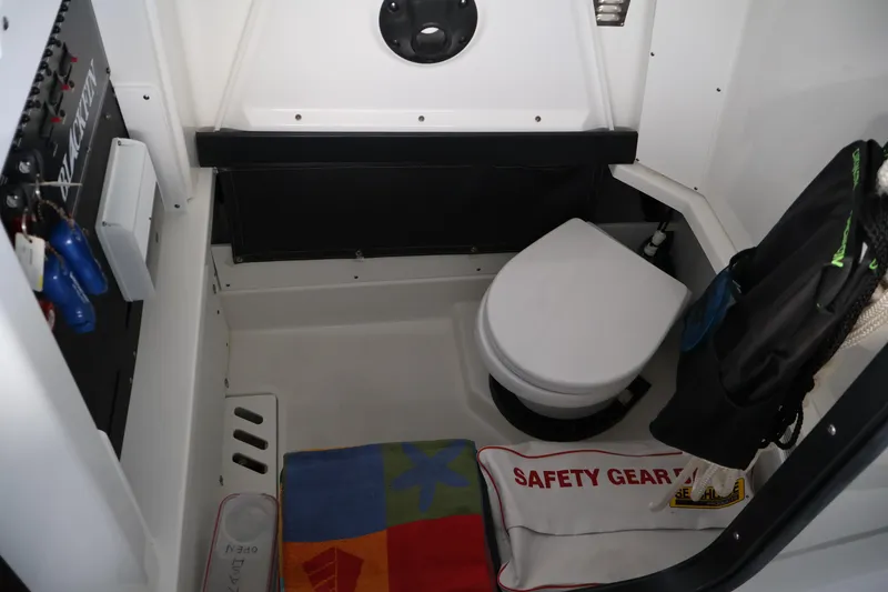 Slide: The Image of Interior of 2021 Blackfin 272 CC boat featuring a compact marine toilet and safety gear. - 16