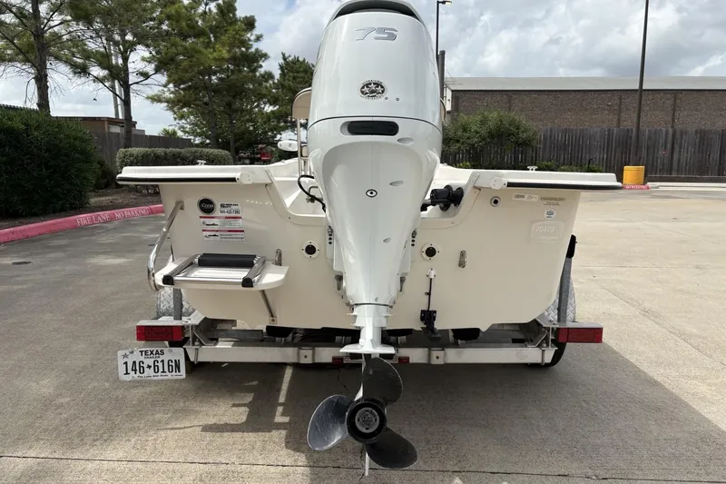 Slide: The Image of 2024 Carolina Skiff E18 JVX CC boat rear view with outboard motor on trailer. - 4