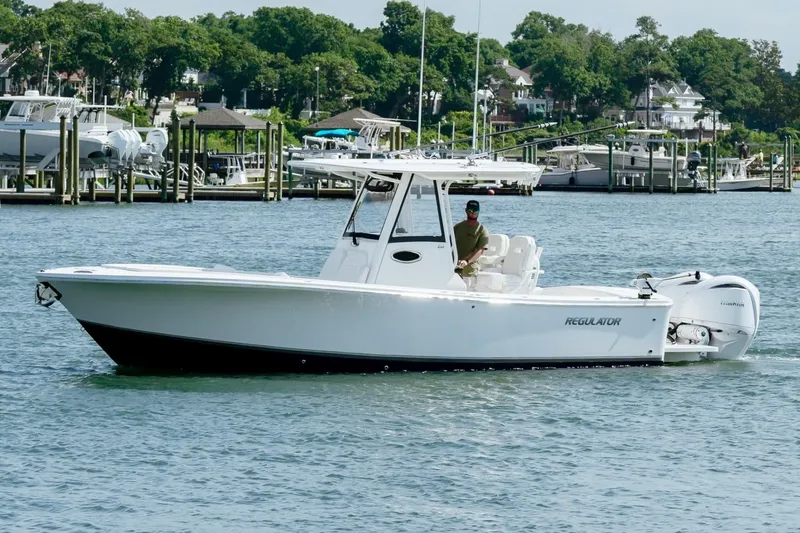Slide: The Image of 2025 Regulator 28 boat cruising on a scenic waterfront with docks and greenery. - 1