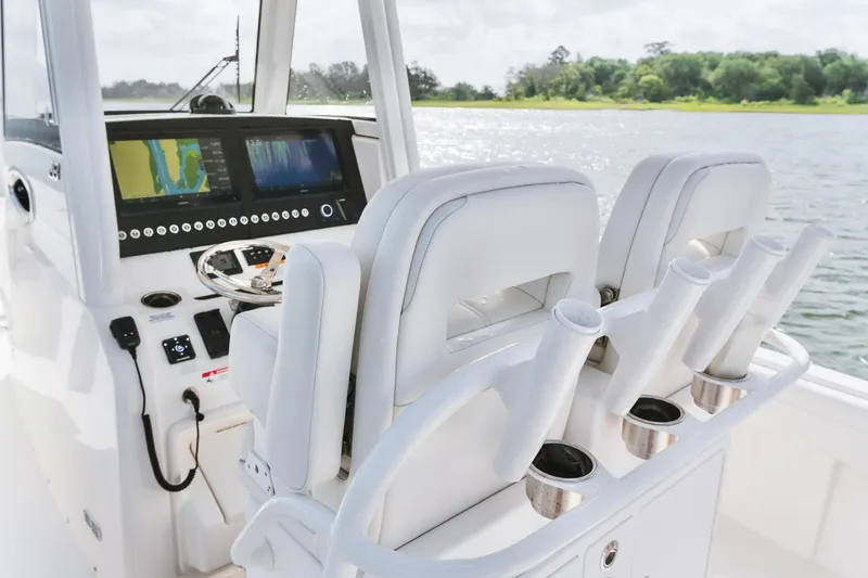 Slide: The Image of 2025 Regulator 28 boat cockpit with dual screens and rod holders on a sunny day. - 15