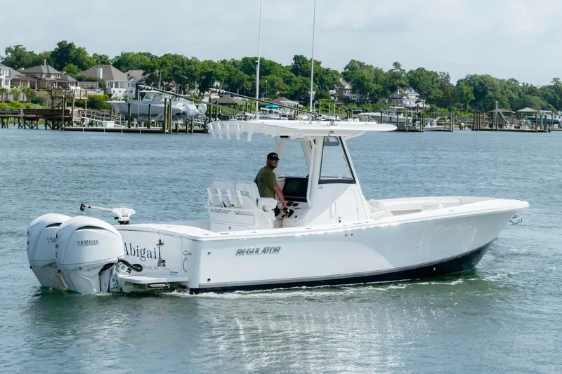 Slide: The Image of 2025 Regulator 28 boat cruising on water with twin Yamaha engines, scenic waterfront background. - 2