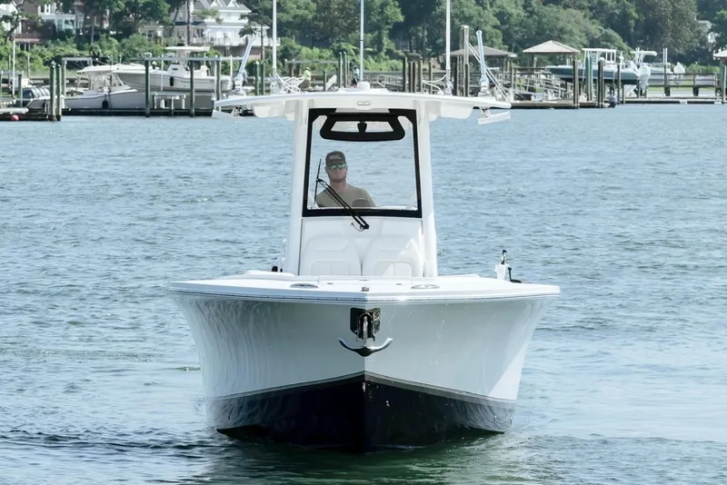 Slide: The Image of 2025 Regulator 28 boat cruising on a calm lake near a marina. - 6