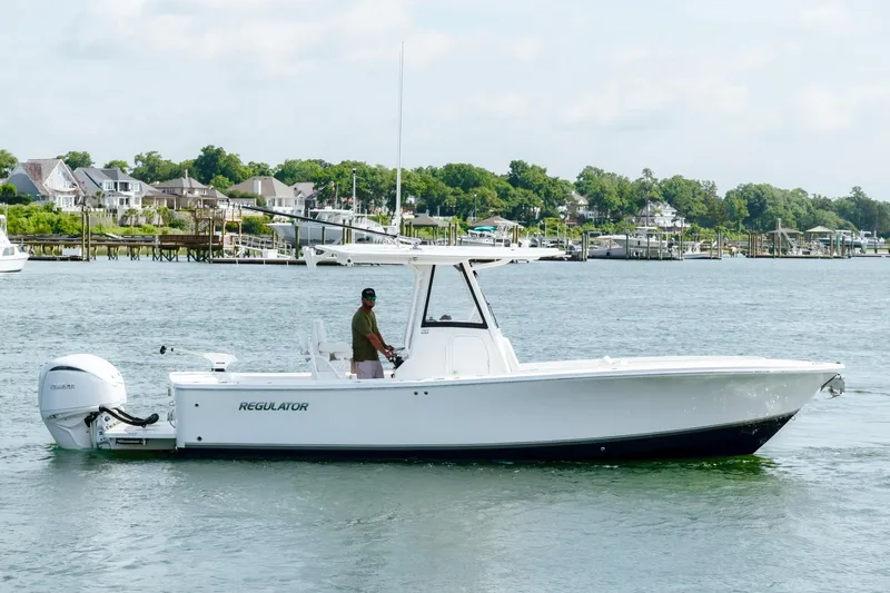 Slide: The Image of 2025 Regulator 28 boat cruising on a scenic waterfront with houses in the background. - 7