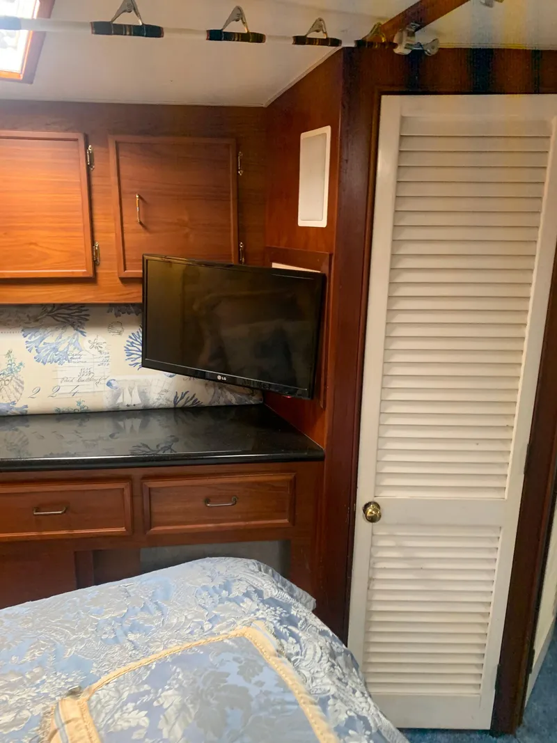 Slide: The Image of 1985 Ocean Yachts 55 Super Sport bedroom with TV, wooden cabinets, and floral bedding. - 33