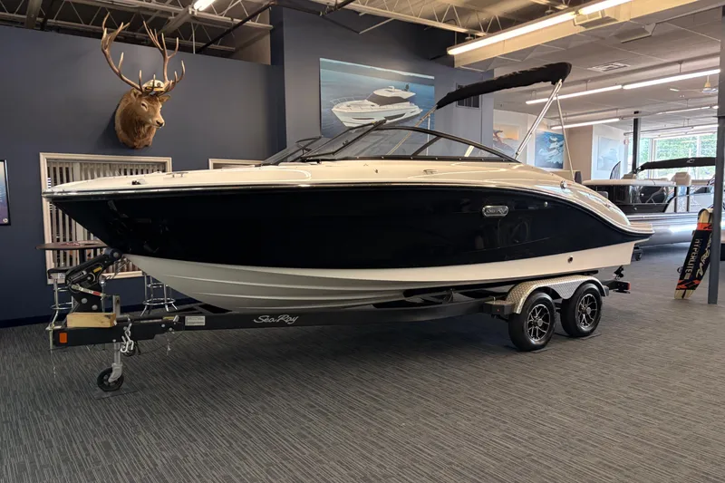 The Image of 2026 Sea Ray 21 SPX boat on trailer in showroom, featuring sleek black and white design. - 0