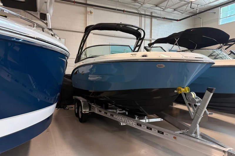 The Image of 2026 Sea Ray SDX 230 boat on trailer in showroom, featuring sleek blue design. - 1