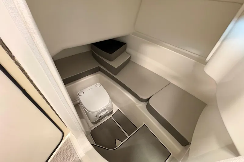 Slide: The Image of Interior of 2026 Sea Ray SDX 230 boat featuring a compact marine toilet. - 13