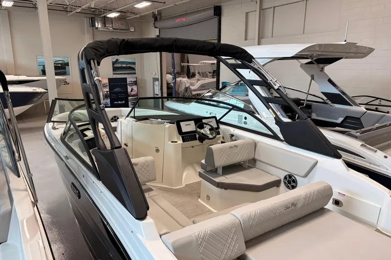 Slide: The Image of 2026 Sea Ray SDX 230 boat interior with modern seating and sleek design in showroom. - 2