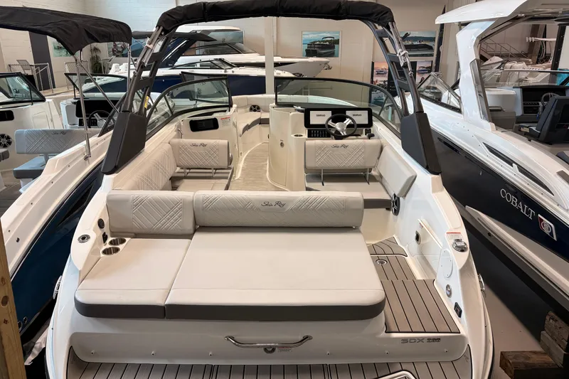 Slide: The Image of 2026 Sea Ray SDX 230 boat interior with luxurious seating and modern dashboard in showroom. - 6