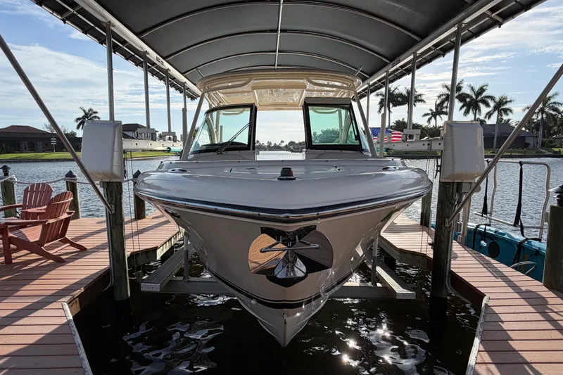 Slide: The Image of 2014 Pursuit DC 265 Dual Console boat docked under a canopy, surrounded by water and palm trees. - 1