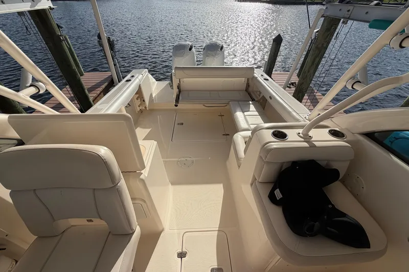Slide: The Image of 2014 Pursuit DC 265 Dual Console boat interior with seating, docked by the water. - 16