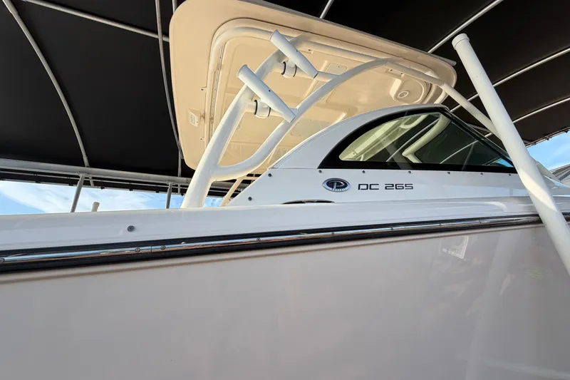 Slide: The Image of 2014 Pursuit DC 265 Dual Console boat under a canopy, showcasing sleek design. - 4