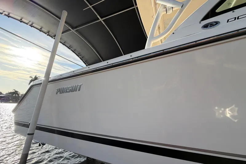 Slide: The Image of 2014 Pursuit DC 265 Dual Console boat docked under canopy, side view. - 5