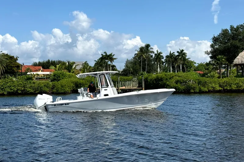 The Image of 2026 Blazer Bay Makaira 2800 cruising on a scenic waterway with lush greenery. - 0