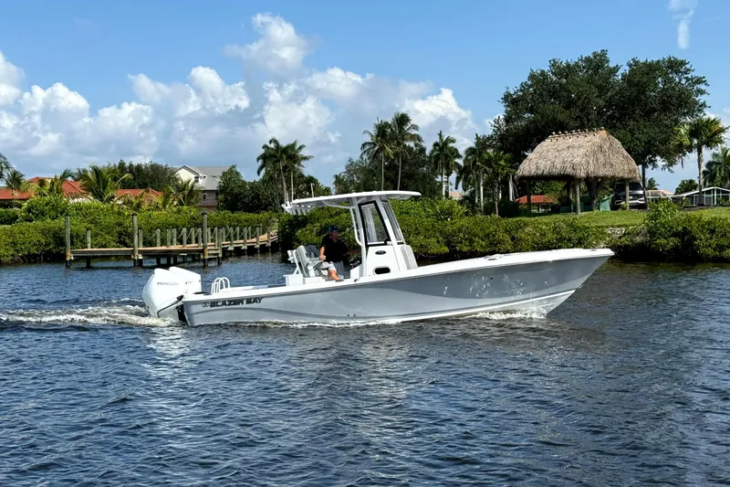 Slide: The Image of 2026 Blazer Bay Makaira 2800 boat cruising on a scenic waterway with lush greenery. - 5