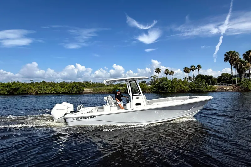 Slide: The Image of 2026 Blazer Bay Makaira 2800 boat cruising on a sunny day with palm trees in the background. - 12
