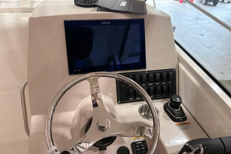 Slide: The Image of Helm of 2026 Boston Whaler 285 Conquest with steering wheel and navigation controls. - 16