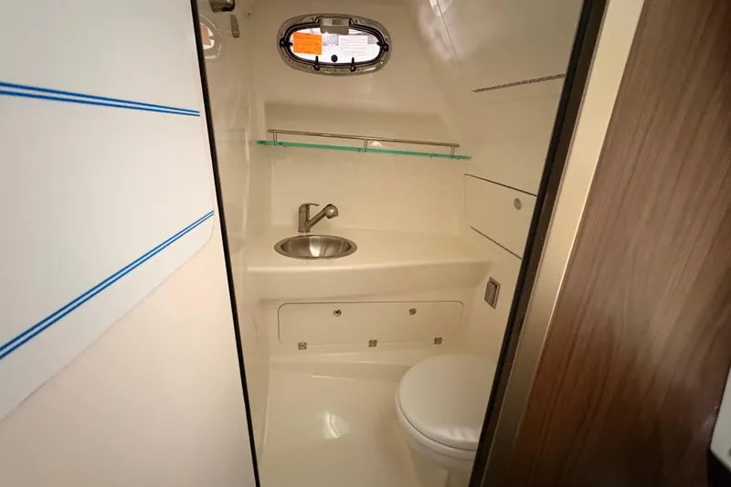 Slide: The Image of 2026 Boston Whaler 285 Conquest bathroom with sink, toilet, and porthole window. - 19