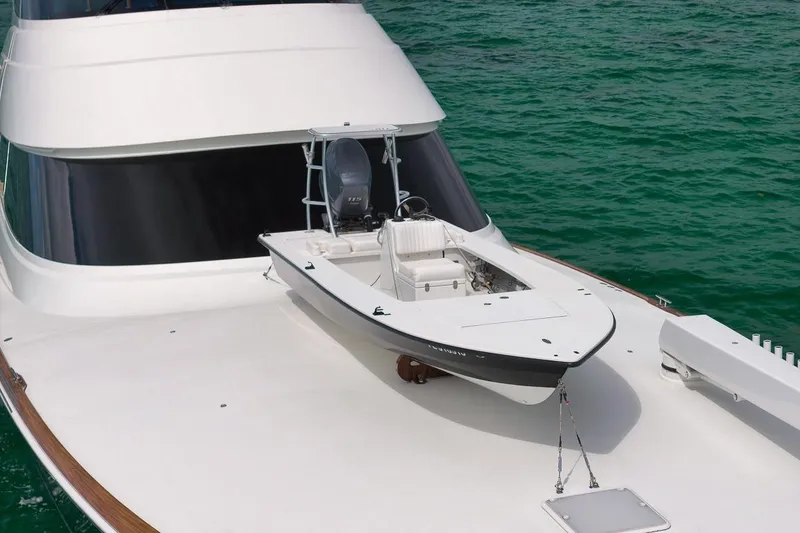 Slide: The Image of 2018 Viking 92 Sky Bridge yacht with a small boat on deck, cruising in clear waters. - 10
