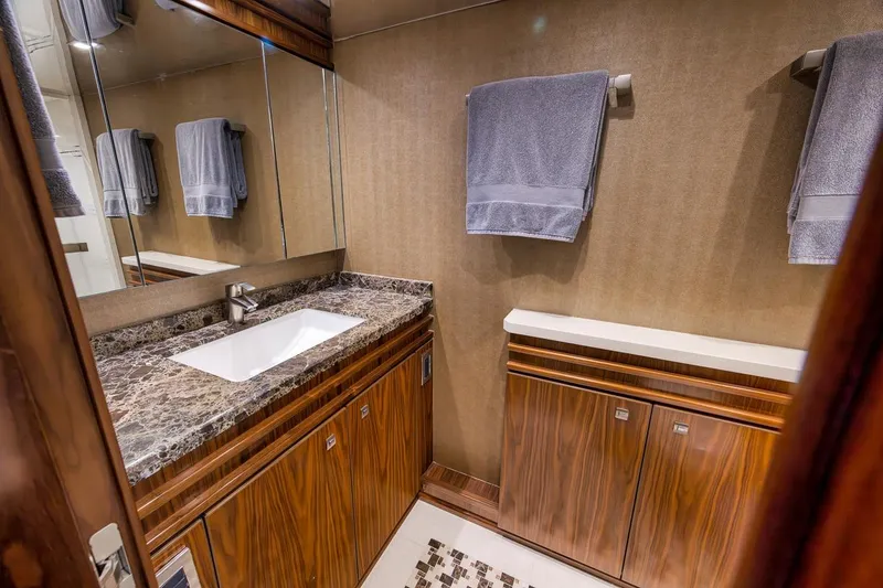 Slide: The Image of Luxurious bathroom in 2018 Viking 92 Sky Bridge yacht with marble countertop and wooden cabinetry. - 104