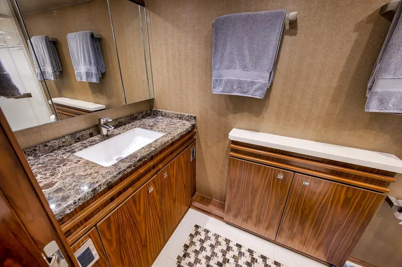 Slide: The Image of Luxurious bathroom in 2018 Viking 92 Sky Bridge yacht with marble countertop and wooden cabinetry. - 105