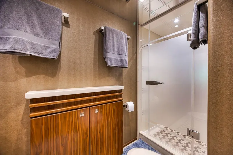 Slide: The Image of Luxurious bathroom in 2018 Viking 92 Sky Bridge yacht with modern shower and wooden cabinetry. - 107