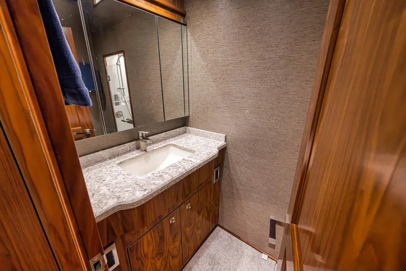 Slide: The Image of Luxurious bathroom in 2018 Viking 92 Sky Bridge yacht with marble countertop and wooden cabinetry. - 118