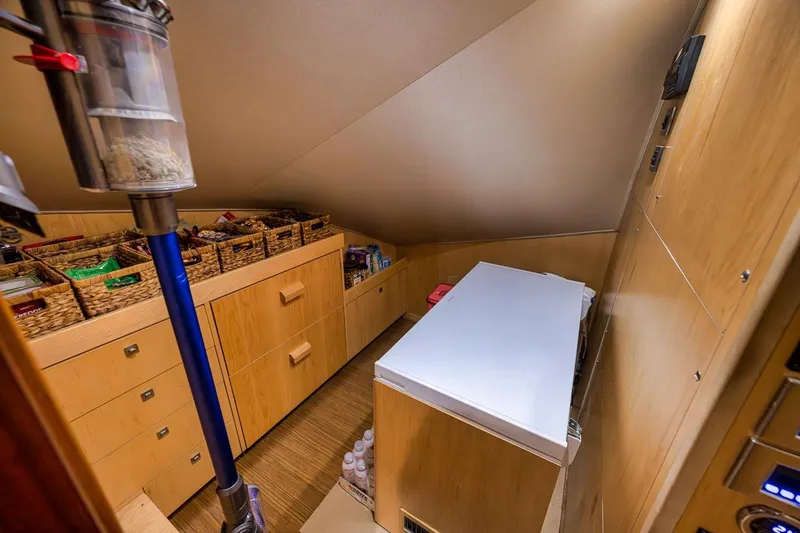Slide: The Image of Storage area in 2018 Viking 92 Sky Bridge yacht with organized shelves and vacuum cleaner. - 124