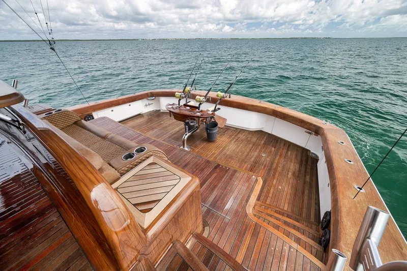 Slide: The Image of Luxurious 2018 Viking 92 Sky Bridge yacht deck with fishing rods, wooden finish, and ocean view. - 32
