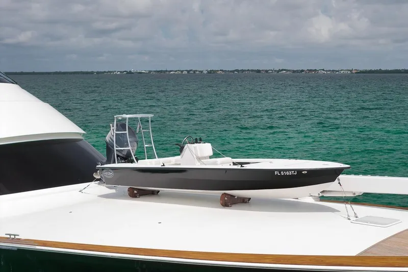 Slide: The Image of 2018 Viking 92 Sky Bridge yacht with a small boat on deck, ocean backdrop. - 9