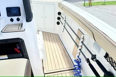 Slide: The Image of 2025 Yamaha Boats 222 FSH Sport E interior with fishing rod holders and control panel. - 16