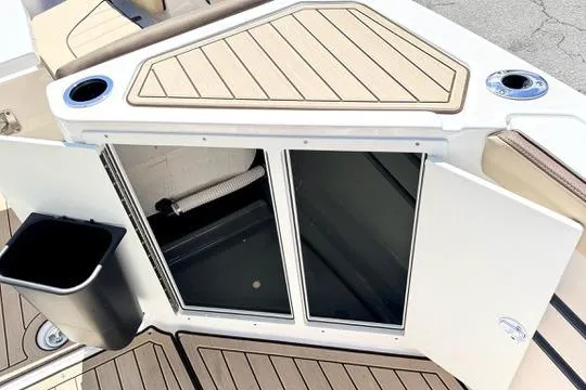 Slide: The Image of 2025 Yamaha Boats 222 FSH Sport E storage compartment with cup holders and trash bin. - 22
