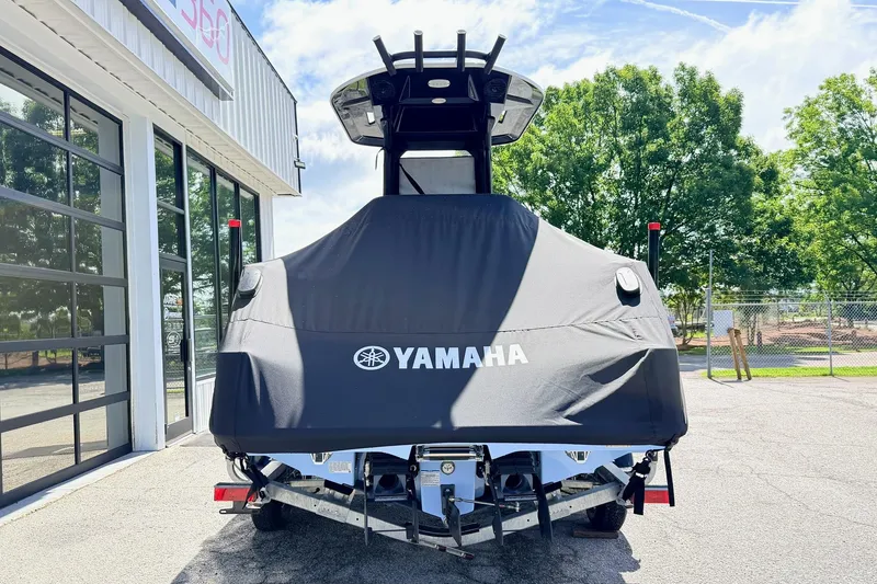 Slide: The Image of 2025 Yamaha Boats 222 FSH Sport E covered, parked outdoors near a building. - 3