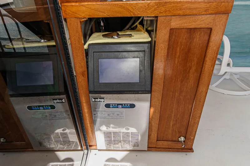 Slide: The Image of Ice maker in 1991 Californian 55 Cockpit Motor Yacht, wooden cabinetry, and reflective surfaces. - 18