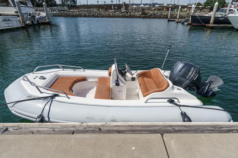 Slide: The Image of Inflatable boat with Yamaha motor docked at marina, featuring tan seating and sleek design. - 58
