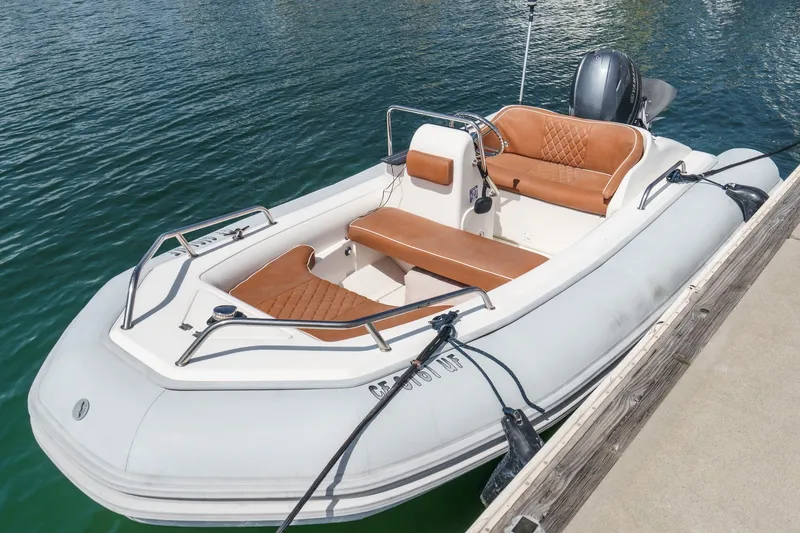 Slide: The Image of A small inflatable boat with tan seating docked on clear water. - 59