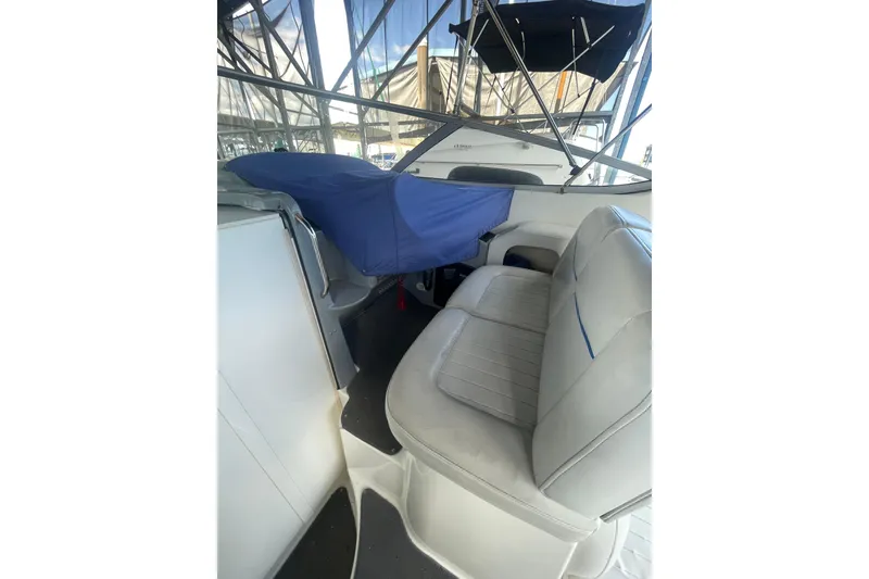 Slide: The Image of Interior of a 2006 Bayliner 305 boat with white seating and blue cover. - 10
