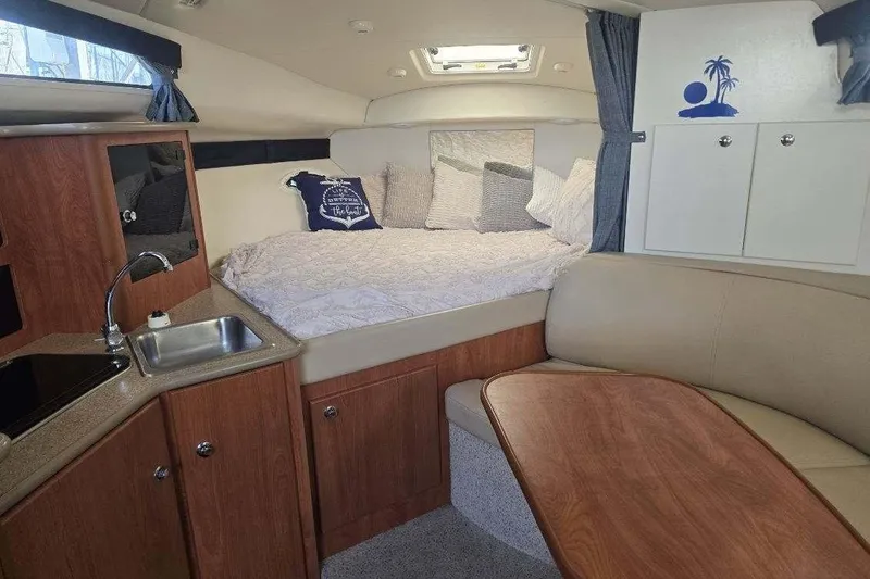 Slide: The Image of 2006 Bayliner 305 cabin interior with cozy bed, kitchenette, and seating area. - 16