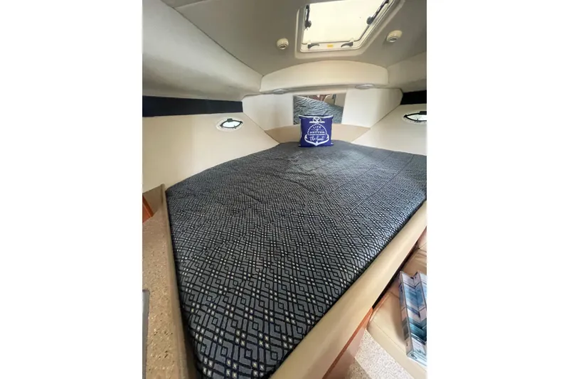 Slide: The Image of 2006 Bayliner 305 cabin interior with patterned bedding and nautical-themed pillow. - 17
